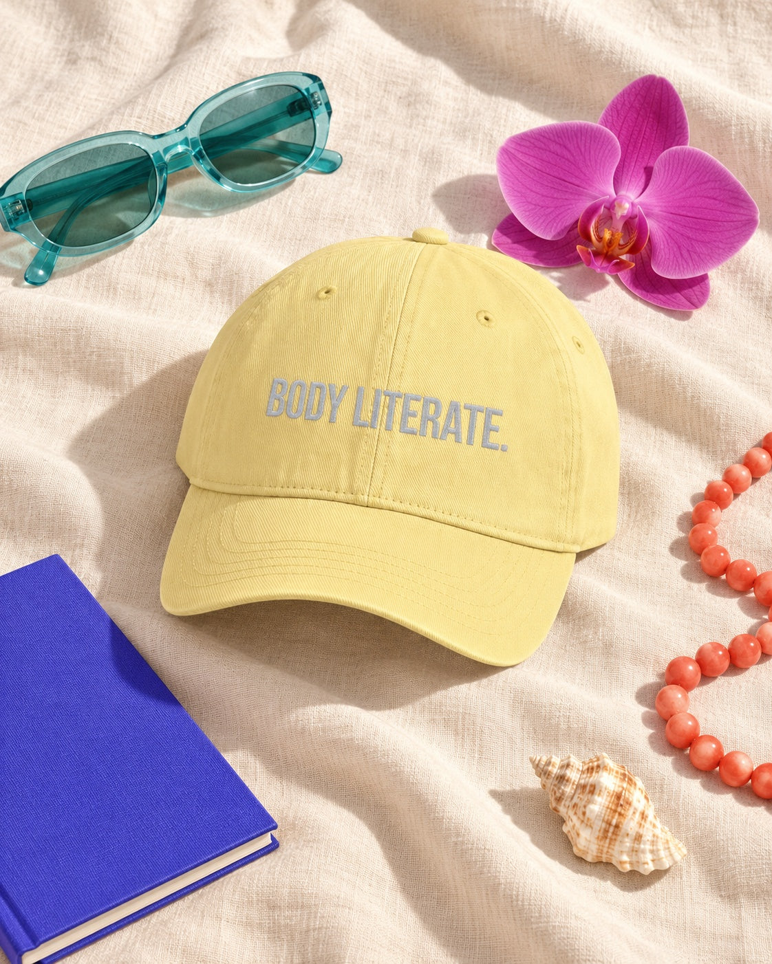 Butter yellow BODY LITERATE. embroidered washed cotton dad hat in a colorful editorial flat lay